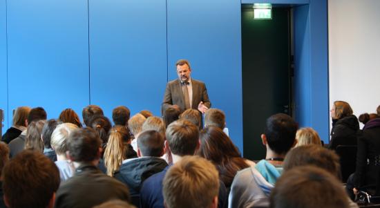 7. November 2012: Franz Thönnes spricht in Berlin zu SchülerInnen des Lessing-Gymnasiums (Foto: SPD) Franz Thönnes vor blauer Kulisse und 85 Norderstedter SchülerInnen