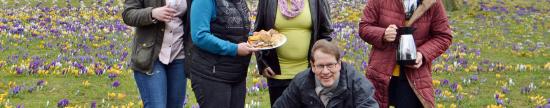 "Krokuskaffe" für Gero Storjohann (CDU). Umgeben von bis zu 5.000 Blumengewächsen feiern Leezens CDU-Frauen den Frühling (Foto: CDU). Vier Frauen mit Kaffee, Kuchen und Gero Storjohann auf einer Wiese mit Krokussen